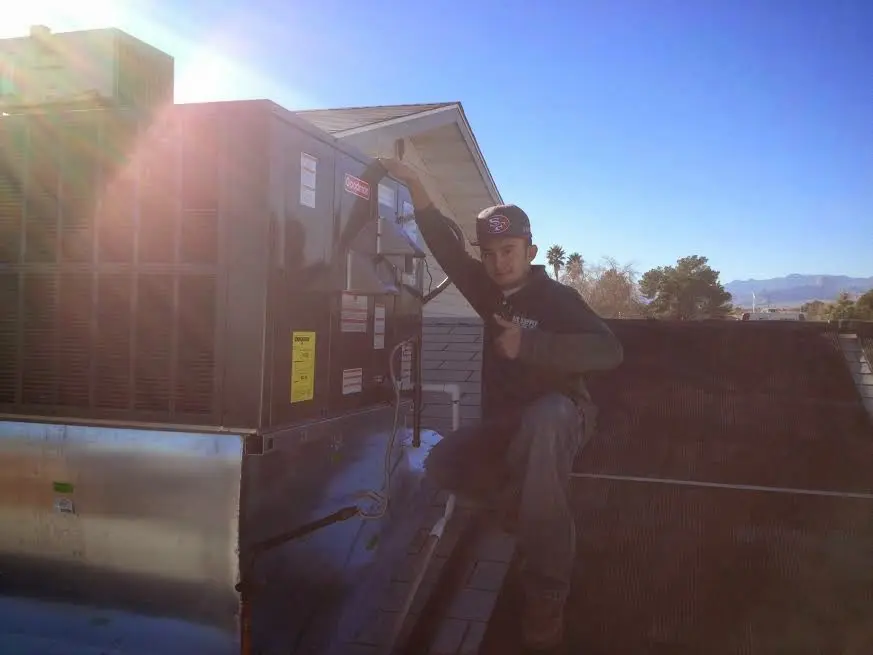 HVAC technician performing AC Tune-Up on a rooftop unit in Desert Hot Springs